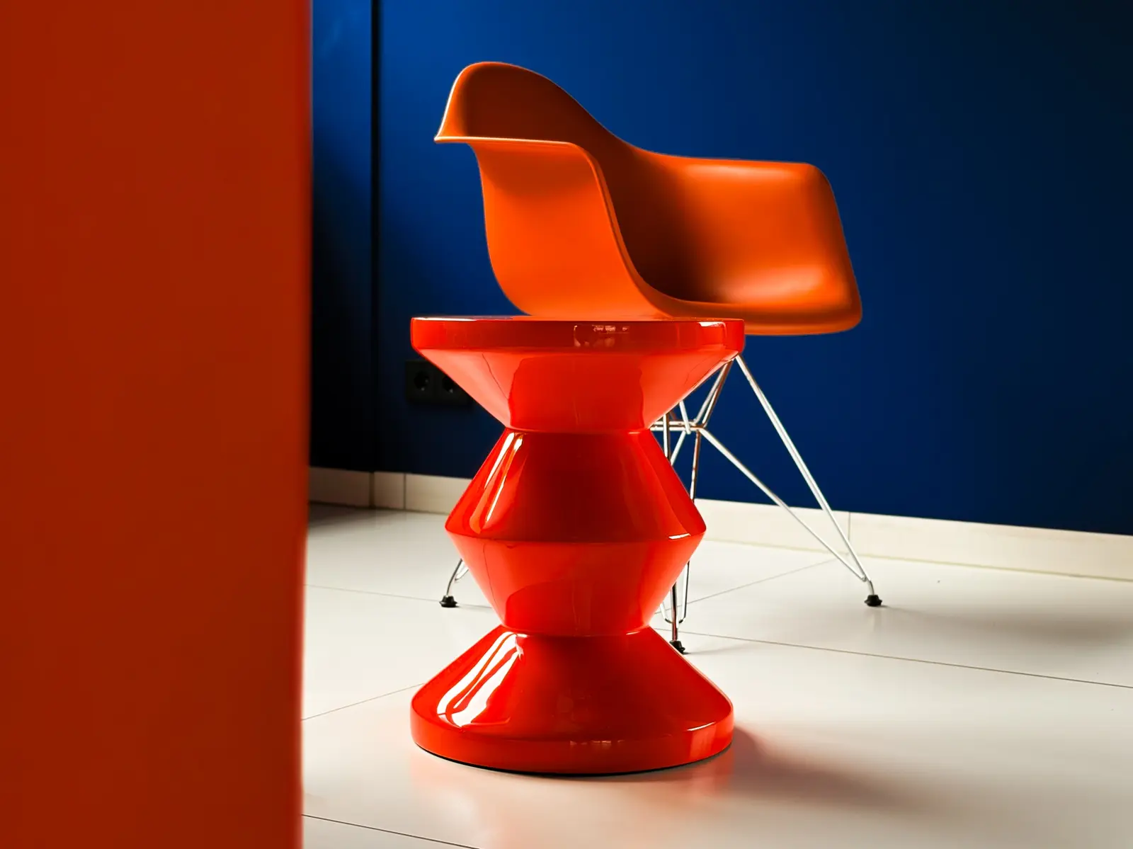 Orangefarbener Designstuhl mit rotem Beistelltisch