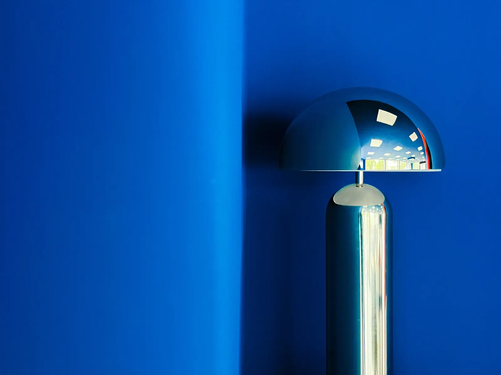 Spiegelleuchte vor leuchtend blauer Wand